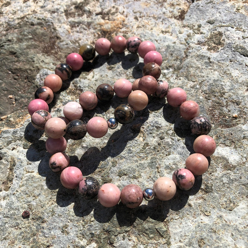 Rhodonite 10mm Bead Stretch Bracelet resting on rock ledge